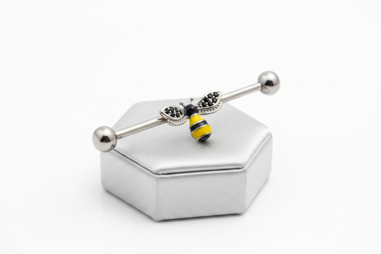 Honey Bee Industrial Ear Barbell in 316l stainless steel on a silver jewelry display.