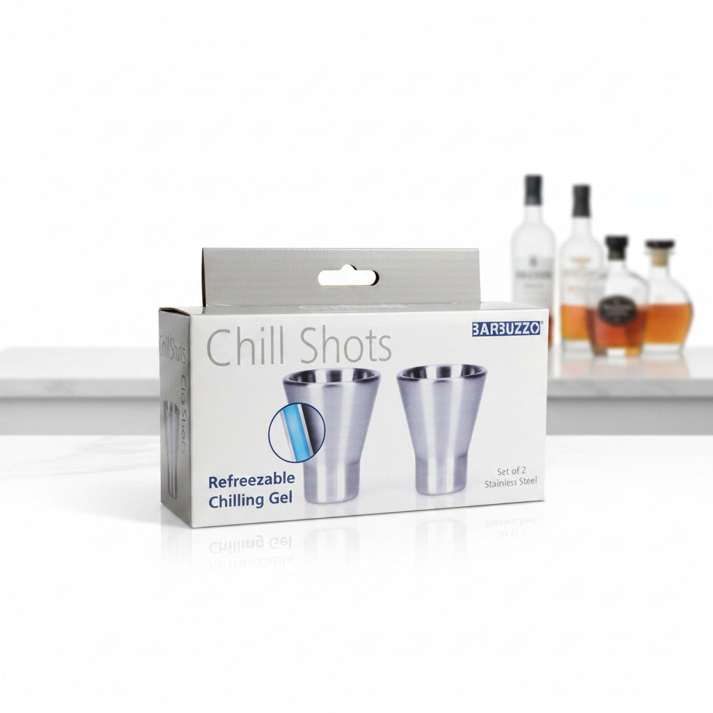 Chill Shots Freezable Stainless Steel Novelty Shot Glass Set on a white surface with blurred alcohol bottles in the background showing close up detail of packaging and brand.