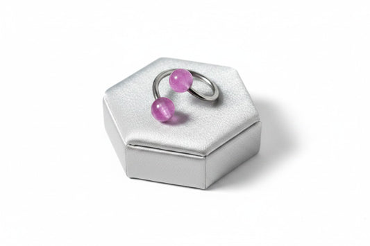 Purple Acrylic Glow Curled Barbell in 316l stainless steel on a silver silk jewelry display.