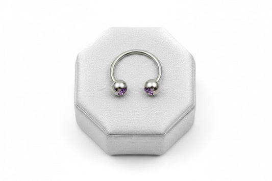 Purple Crystal Steel Horseshoe Curved Barbell in 316l stainless steel on a silver silk jewelry display in close up detail.