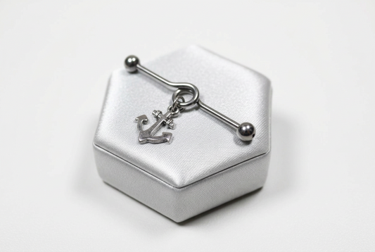 Dangling Anchor Industrial Ear Barbell in 316l stainless steel on a silver silk jewelry display.