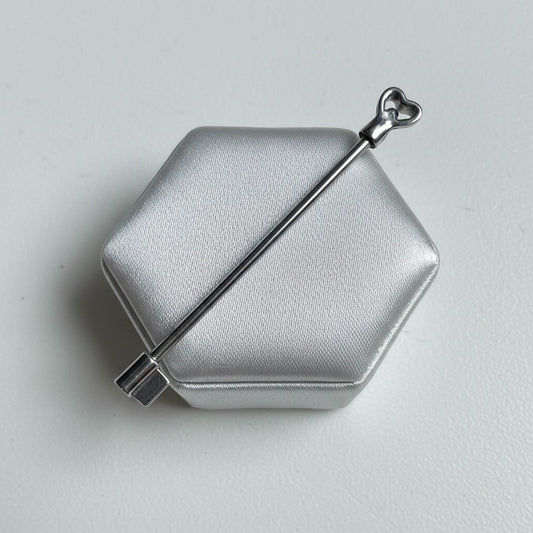 Key Industrial Ear Barbell in 316l stainless steel on a silver silk jewelry display.