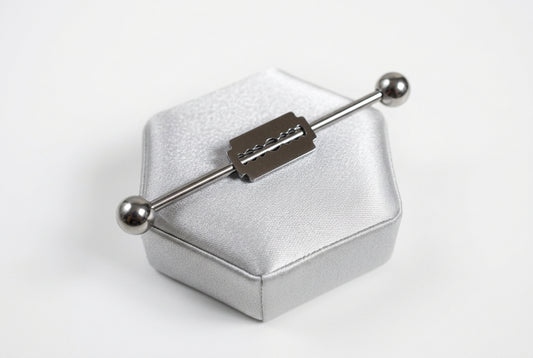Razor Blade Industrial Ear Barbell in 316l stainless steel on a silver silk jewelry display.