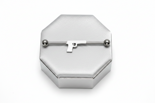 Handgun Industrial Ear Barbell in 316l stainless steel on silver silk jewelry display.