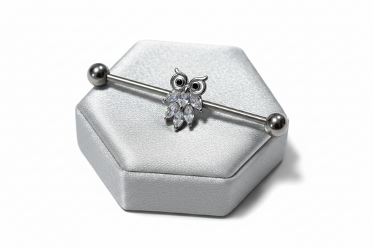 Owl Industrial Ear Barbell in 316l stainless steel on a silver silk jewelry display.