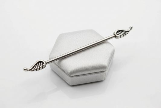 Wings Industrial Ear Barbell in 316l stainless steel on a silver silk jewelry display.