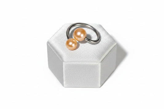Orange Acrylic Glow Curled Barbell in 316l stainless steel on a silver silk jewelry display.