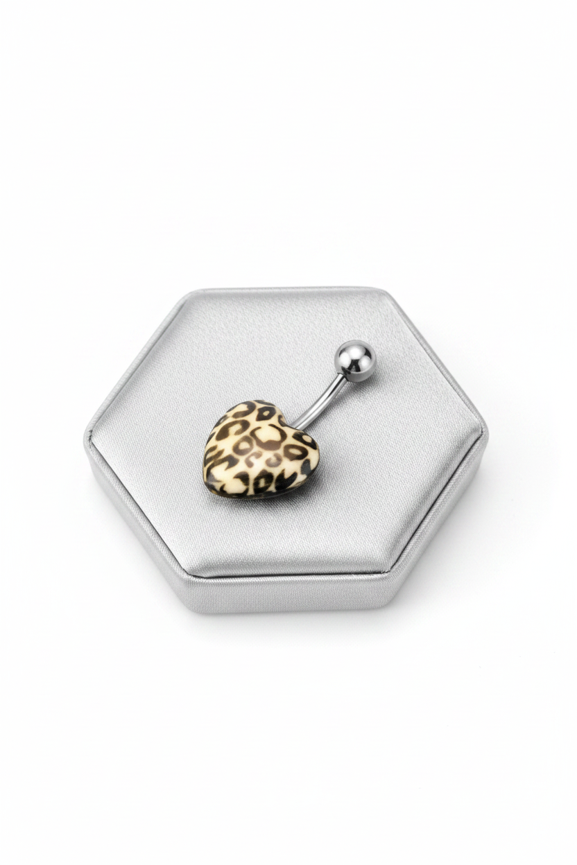 White Leopard Print Heart Acrylic Belly Button Ring in 316l stainless steel on a silver jewelry display angled left.