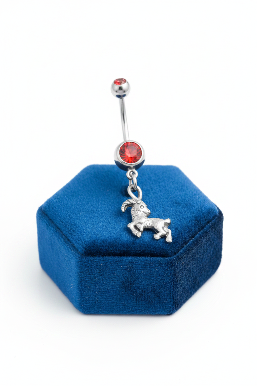 Red Crystal Capricorn Belly Button Ring in 316l stainless steel on a blue velvet jewelry display.