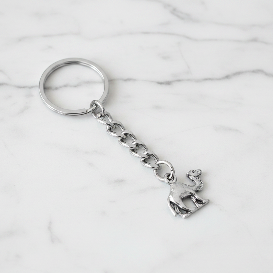 Desert Camel Handmade Pewter Charm Keychain on a white marble surface.