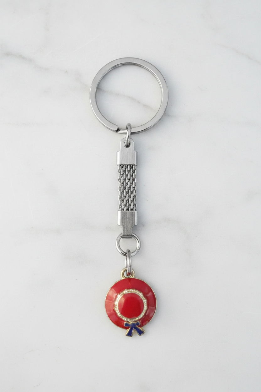 Red and Purple Enamel Hat Handmade Silver Plated Charm Keychain on a white marble surface.