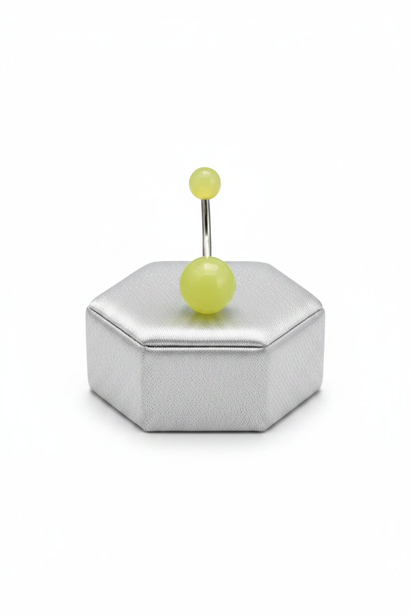 Yellow Glow Acrylic Belly Button Ring in 316l stainless steel on a silver jewelry display.
