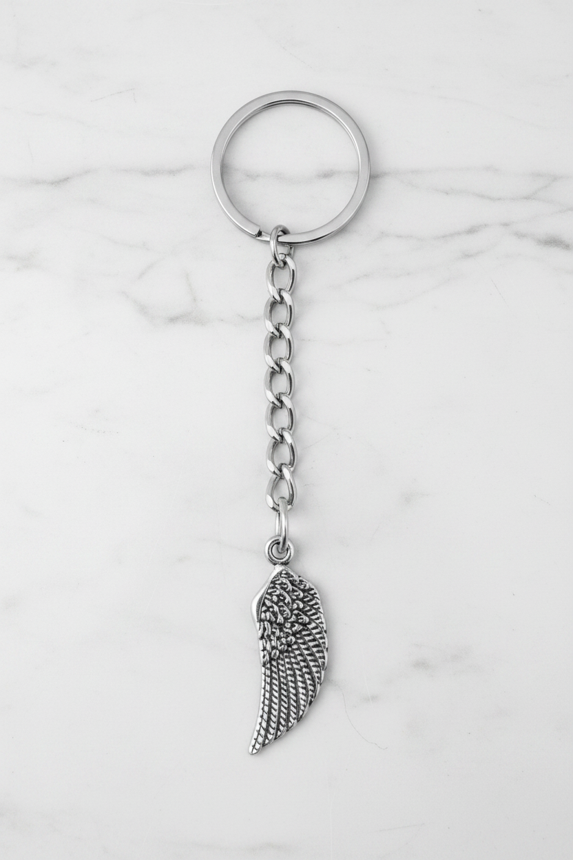 Bird Wing Handmade 316L Stainless Steel Charm Keychain on a white marble surface.