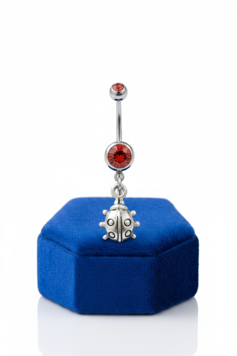 Red Crystal Lady Bug Belly Button Ring in 316l stainless steel on a small blue velvet jewelry display.