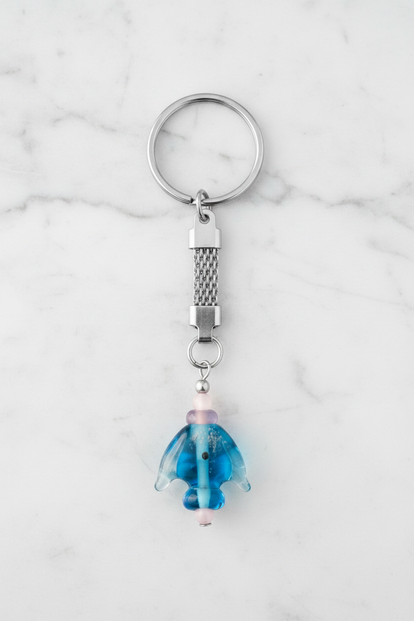 Aqua Glass Fish Handmade Steel Plated Keychain on a white marble surface.