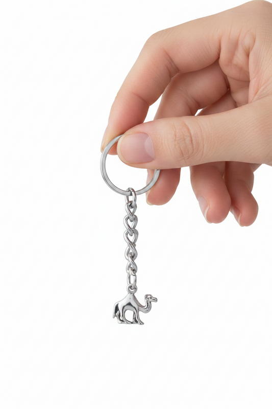 Desert Camel Handmade Pewter Charm Keychain held by  a hand showing scale.