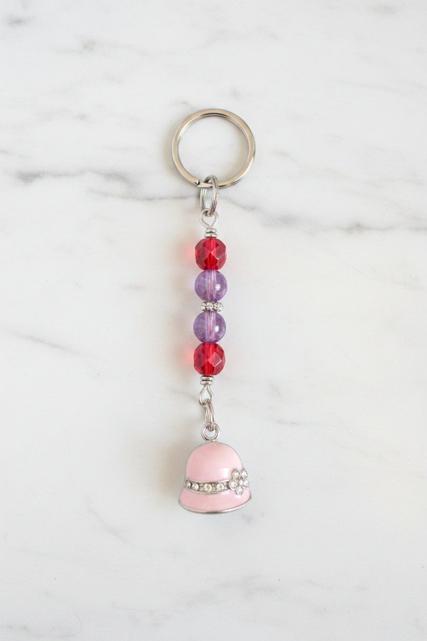 Pink Enamel Hat Handmade Beaded Mini Keychain on a white marble surface.
