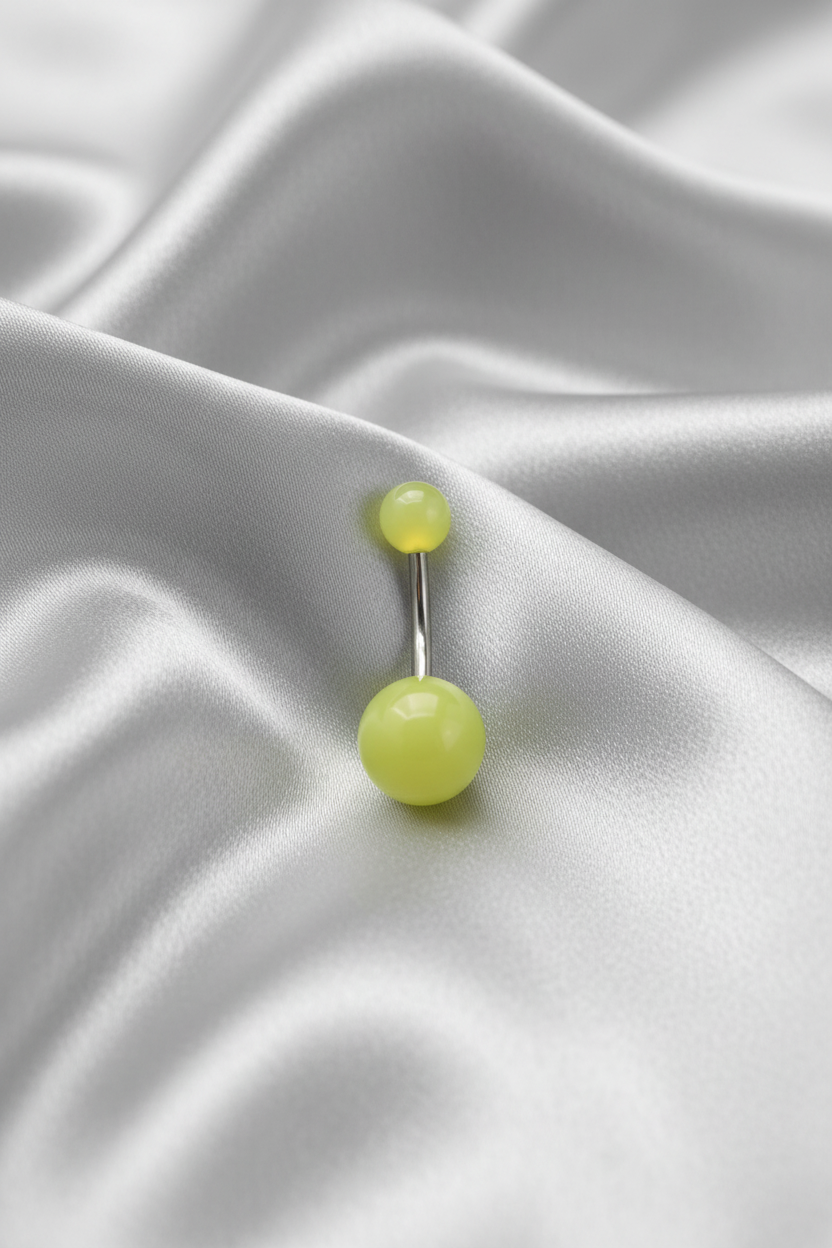 Yellow Glow Acrylic Belly Button Ring in 316l stainless steel on silver silk fabric.