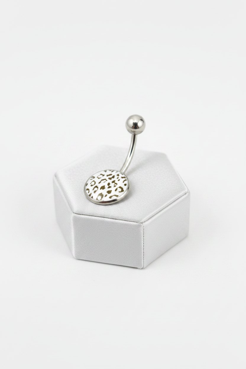 White Leopard Print Belly Button Ring in 316l stainless steel on a silver silk jewelry display angled left.