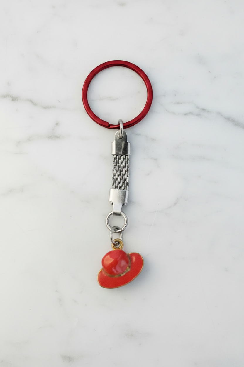 Red Enamel Hat Handmade Silver Plated Charm Keychain on  a white marble surface.