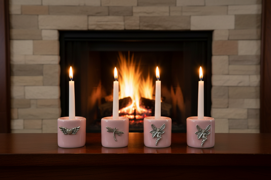 Pink Assorted Designs Ceramic Mini Candle Holder Set of Four on a wooden table in front of a stone fireplace with a burning fire and candles lit showing a warm glow.
