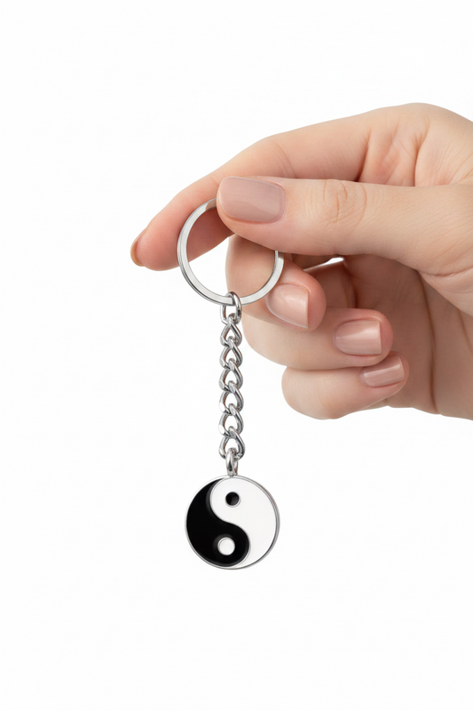 Black and White Enamel Yin Yang Handmade Pewter Charm Keychain held by a hand showing scale.