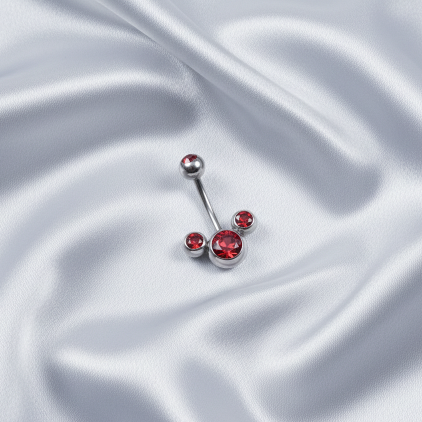 Red Crystal Belly Button Ring in 316l stainless steel on silver silk fabric.