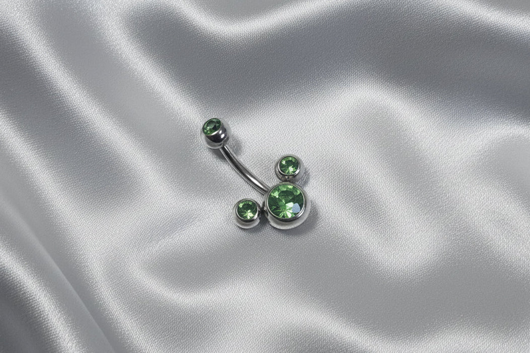 Green Crystal Belly Button Ring in 316l stainless steel on silver silk fabric.