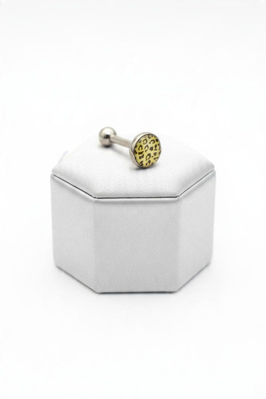 White Leopard Print Tongue Barbell in 316l stainless steel on a silver silk jewelry display.